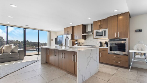 A modern kitchen with a large island, stainless steel appliances, and wooden cabinets.