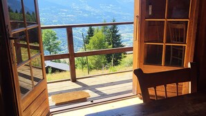 A wooden deck with a view of mountains and a wooden table.