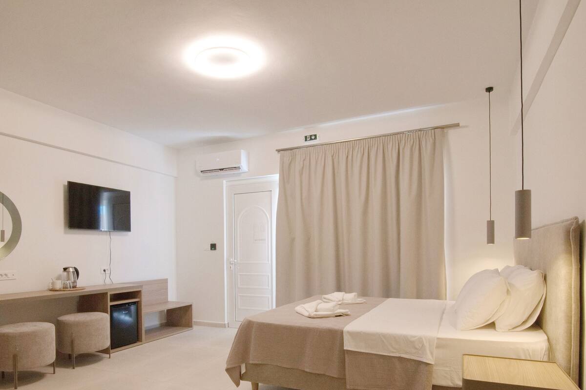 A modern hotel room with a bed, bedside table, and a desk with a chair.