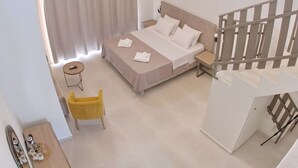 Une chambre à coucher comprenant un lit, une table de chevet, une chaise, une petite table et un escalier.