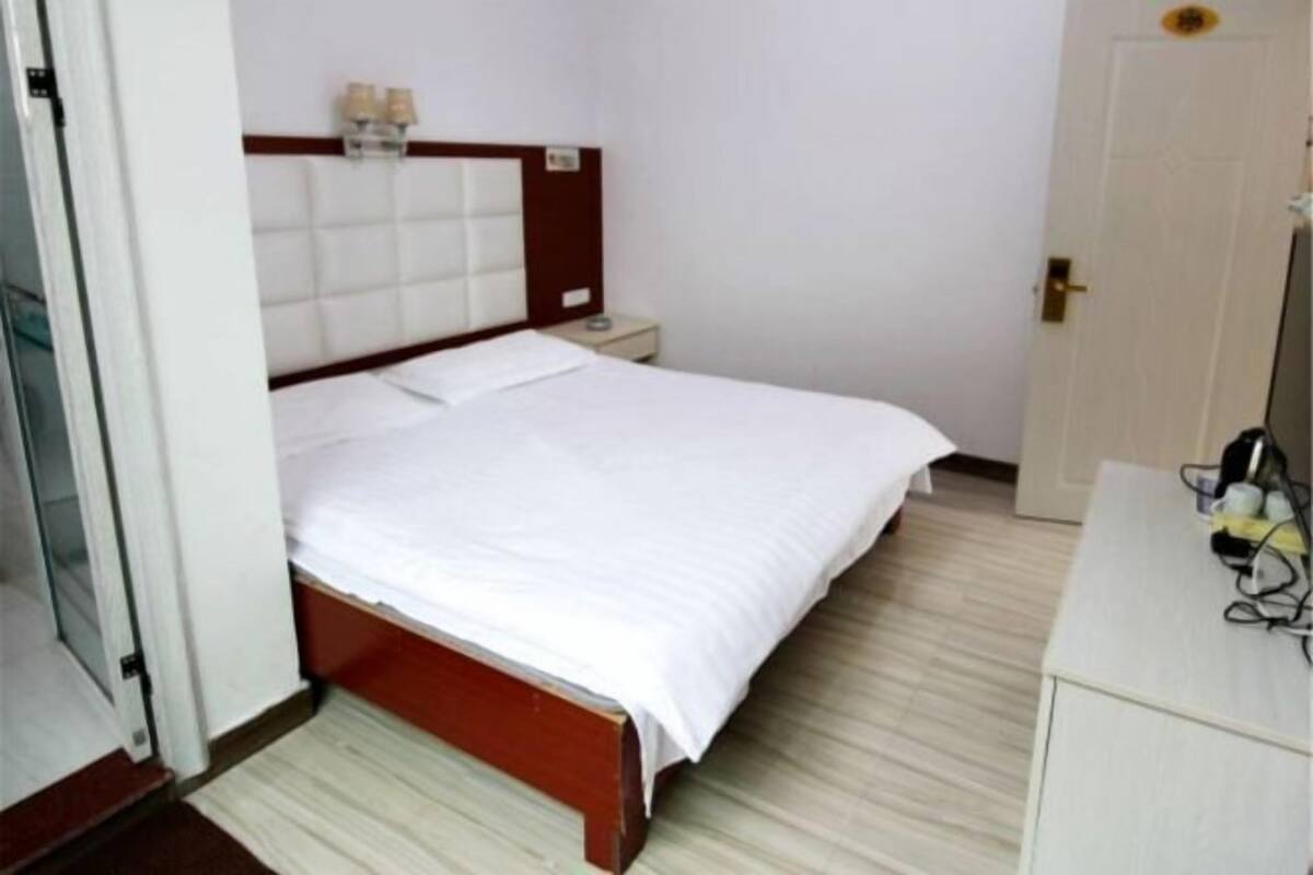 A hotel room with a bed, bedside table, and a door.
