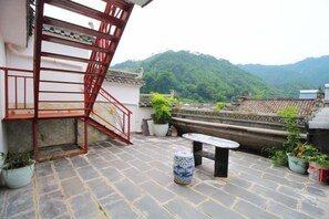 A rooftop terrace with a red metal staircase, potted plants, and a stone floor. - Guiping Country House, Guili Ancient Town (Fuliang)