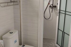 Un baño con inodoro, ducha y puerta de vidrio.