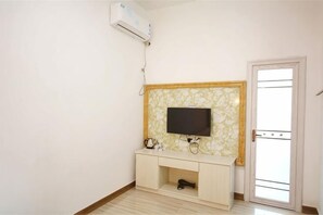 A room with a flat-screen TV on a wooden cabinet, an air conditioning unit, and a door with a glass panel. - Guiping Country House, Guili Ancient Town (Fuliang)