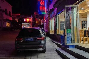 Un coche estacionado en la calle con una fachada comercial a la derecha.