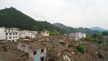 Un pueblo tradicional con edificios de tejados de teja y una colina al fondo, con una mezcla de construcciones residenciales y comerciales.