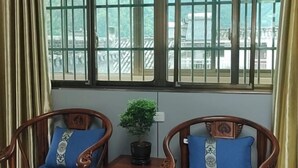 A room with two wooden chairs with blue cushions, a small table with a potted plant, and a window with metal bars. - Guiping Country House, Guili Ancient Town (Fuliang)