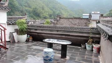 Enjoy a tranquil retreat on this traditional Chinese-style terrace with a stone floor, surrounded by lush green mountains.