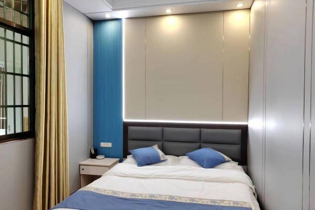 A bedroom with a bed, nightstand, and a window with curtains.