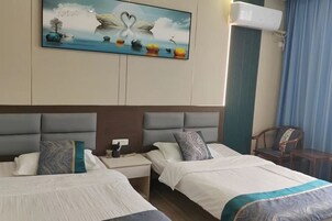 Habitación de hotel con dos camas, un cuadro de un cisne en la pared y un equipo de aire acondicionado.