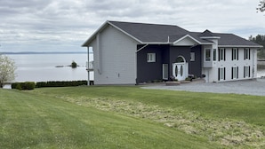 A two-story house with a large front porch and a view of a lake.