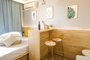 A hotel room with a bed, a small bar area, two bar stools, a sink, and a toilet. - Box Space Xinzhiwan Hotel (Shanghai Bay University City Branch) (Shanghai)