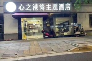 A hotel entrance with a sign, a scooter parked outside, and a pedestrian crossing. - Box Space Xinzhiwan Hotel (Shanghai Bay University City Branch) (Shanghai)