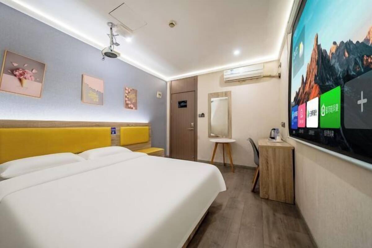 A hotel room with a bed, a desk, a chair, and a large window with a view.