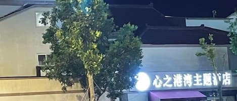 A hotel with a sign indicating it is a hotel. There is a tree in front of the building.