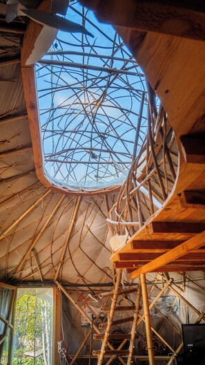 Une pièce dotée d’une structure de plafond en bois, d’un puits de lumière et d’un escalier en colimaçon.