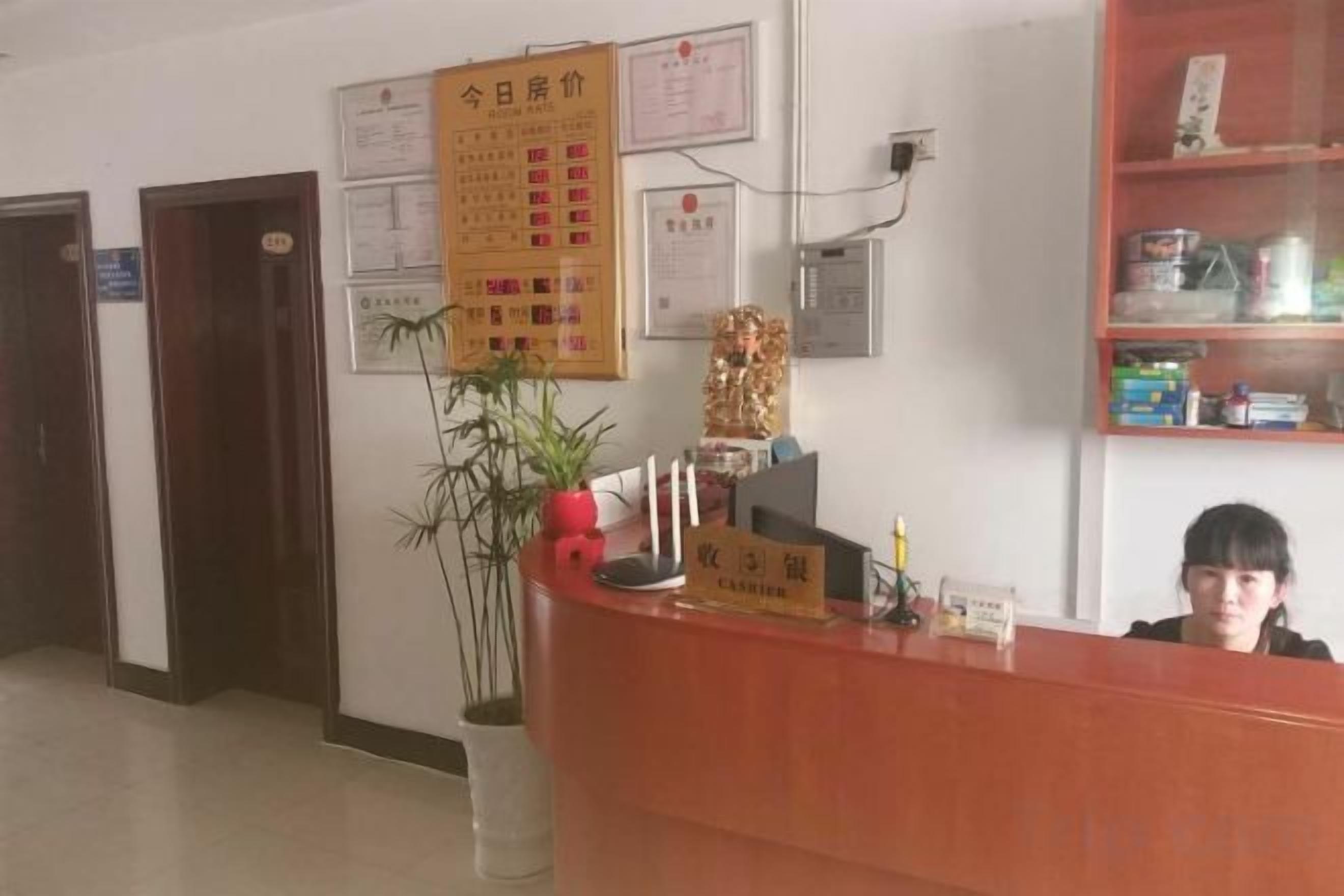 A reception desk with a sign, a potted plant, and a wall with various notices.