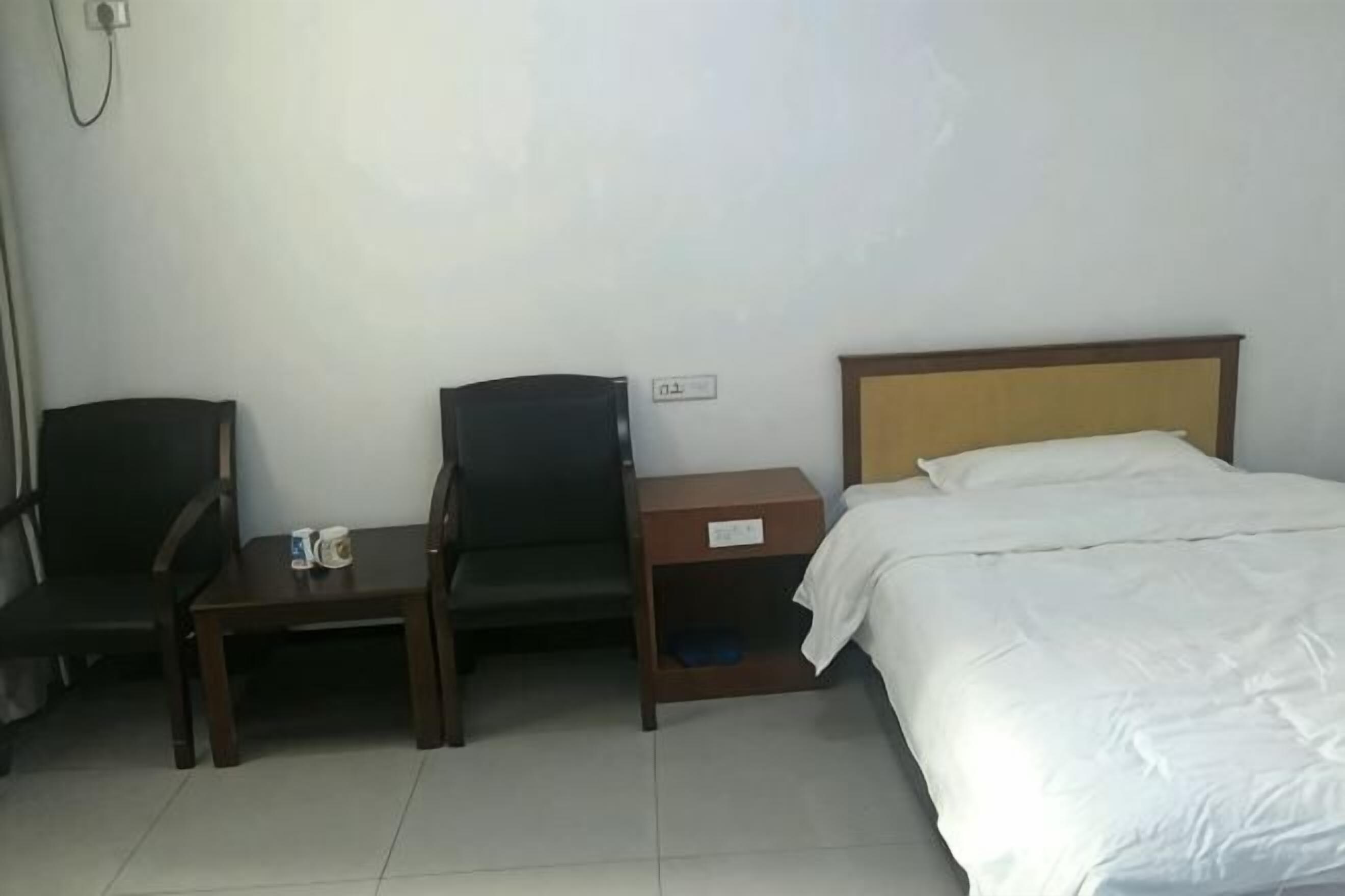 Una habitación de hotel con cama, escritorio, dos sillas y mesita de noche.