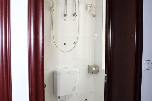 Un baño con ducha, inodoro y dispensador de jabón.