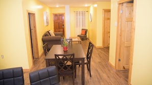 A dining area with a wooden table and chairs, a sofa, and a small table with a plant.