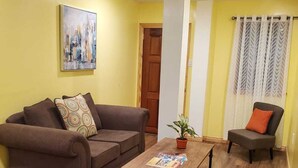 A living room with a brown sofa, a wooden coffee table, and a small armchair with a cushion.
