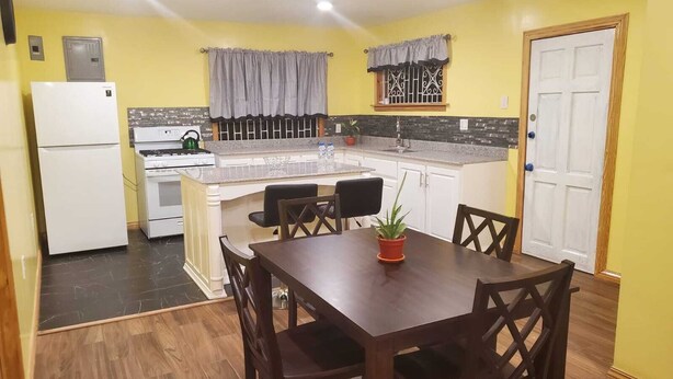 A compact kitchen with a refrigerator, stove, and dining area with chairs and a table.