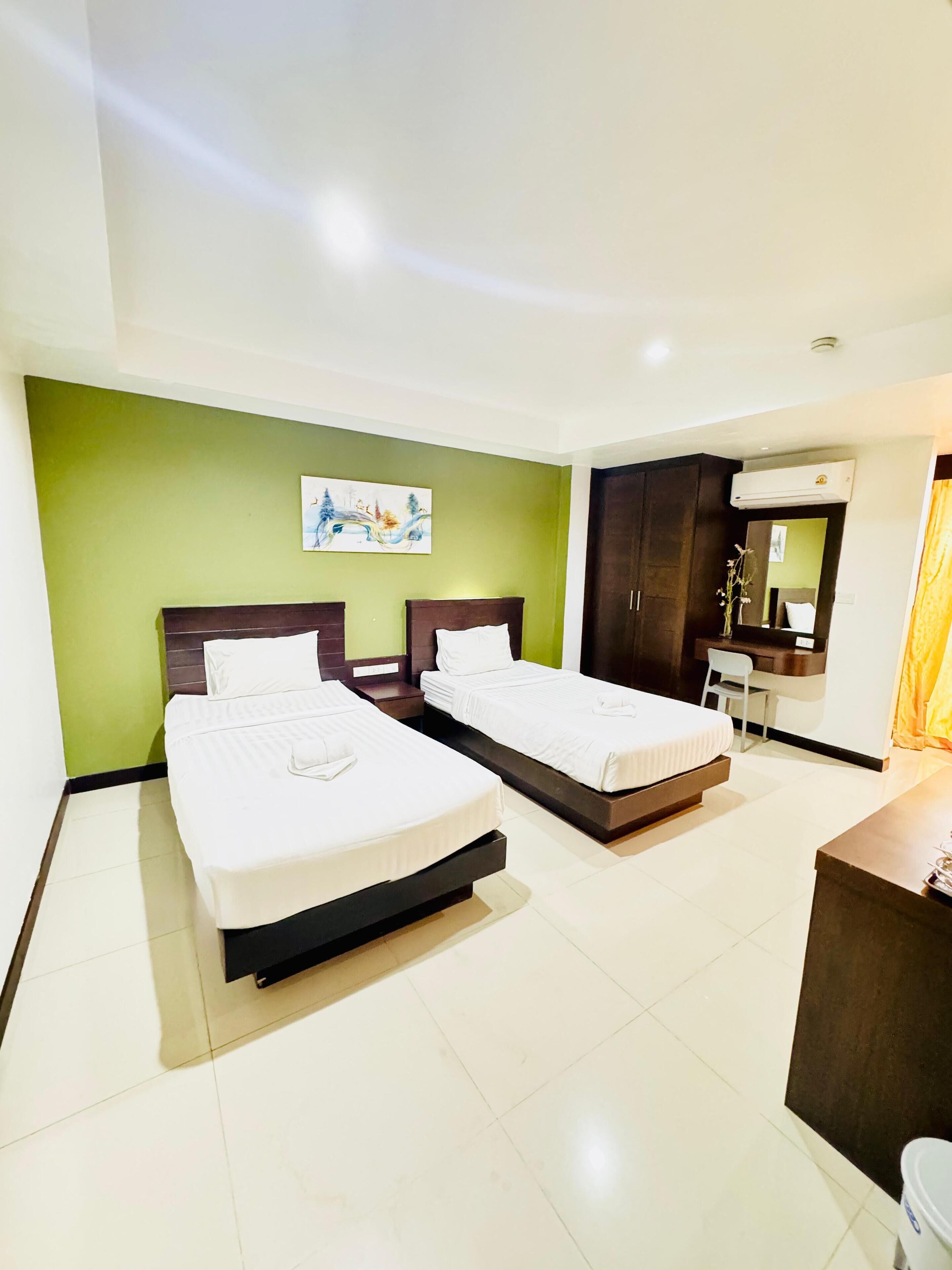 A hotel room with two beds, a desk, a chair, a mirror, and a painting on the wall.