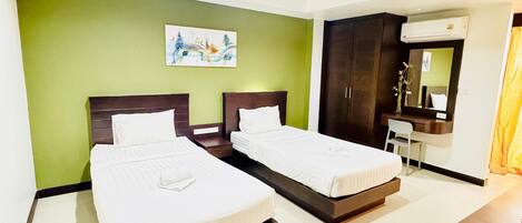 A hotel room with two beds, a desk, a chair, a mirror, and a painting on the wall.
