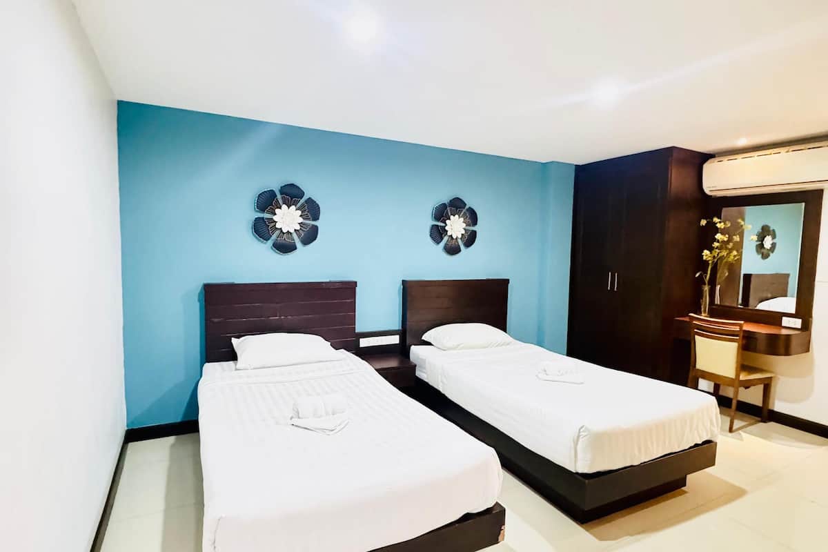 Quarto de hotel com duas camas, uma escrivaninha e um espelho.