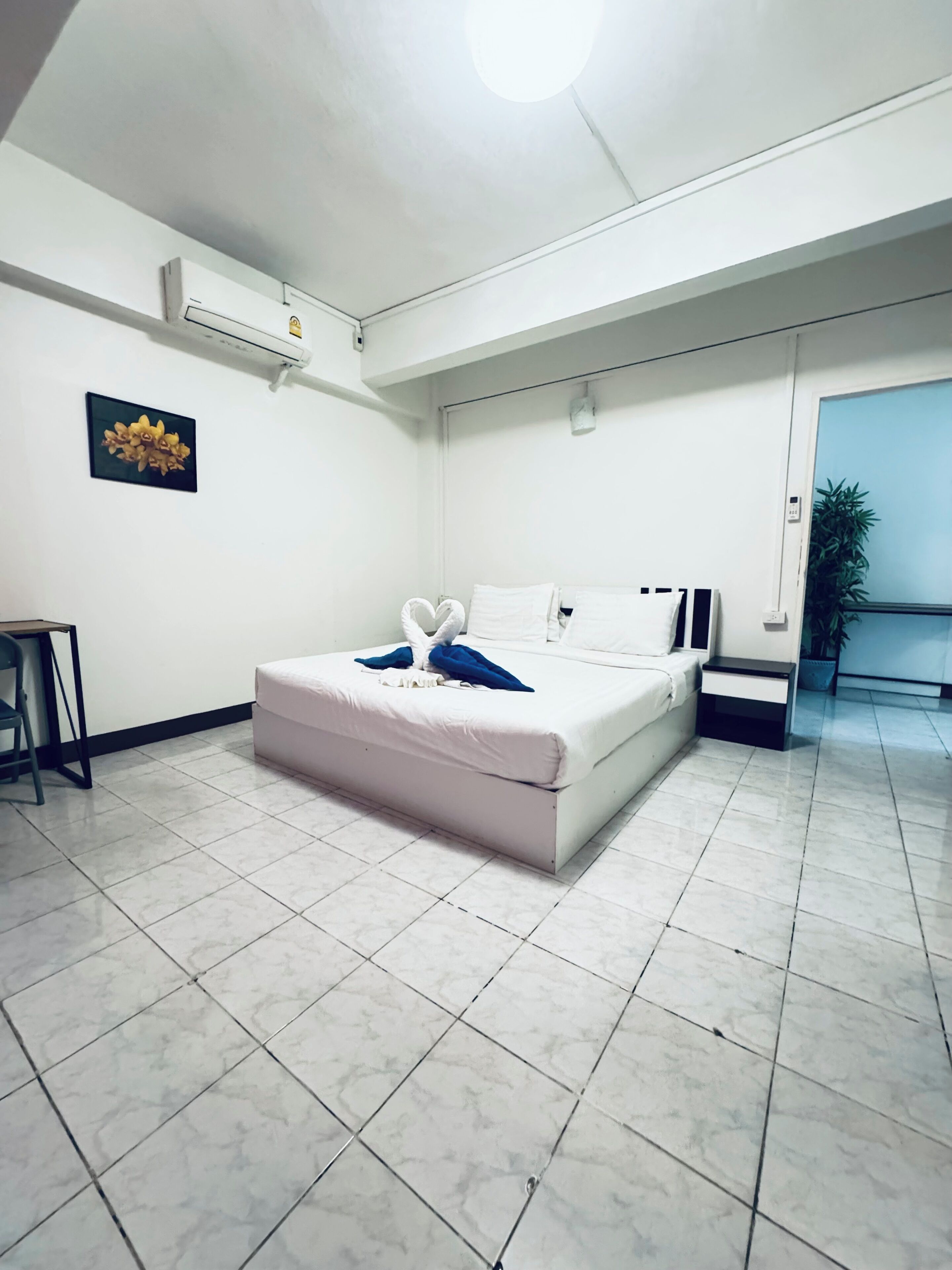 Ein Schlafzimmer mit Bett, Nachttisch, Sessel und einer Topfpflanze.