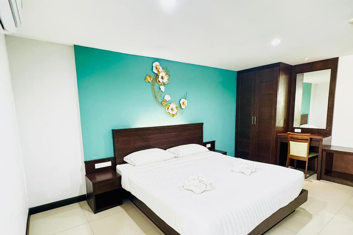 Quarto com cama, mesas de cabeceira, cômoda, espelho e um adorno na parede.