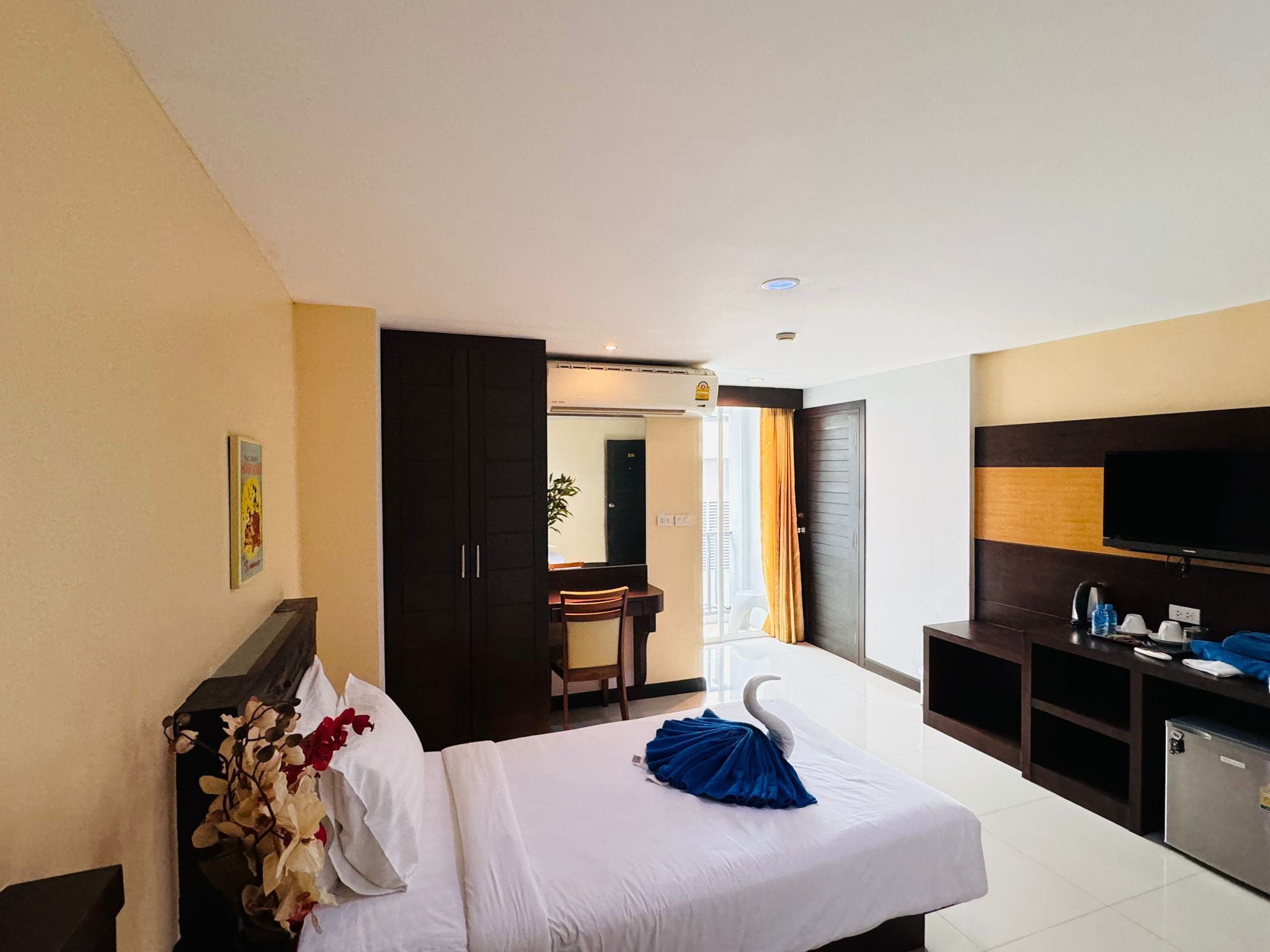 Habitación de hotel con cama, escritorio, televisor y armario.