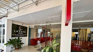 Un intérieur moderne avec un espace d’accueil, des sièges rouges et des plantes en pot.