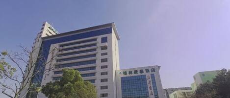 A multi-story building with a modern design, featuring a large glass facade and a sign with Chinese characters.