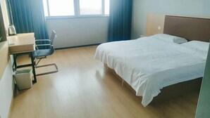 A hotel room with a bed, a desk with a chair, a window with curtains, and a trash bin. - GreenTree Inn Express Hotel (Suqian Xiangwang East Road Suyu Bureau of Education Branch) (Suqian)