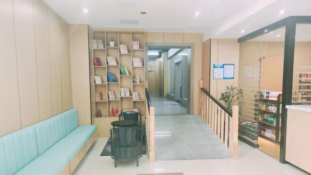 A reception area with a light blue sofa, a small table, and a bookshelf. - GreenTree Inn Express Hotel (Suqian Xiangwang East Road Suyu Bureau of Education Branch) (Suqian)