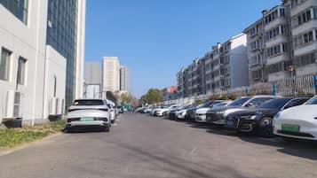 A street lined with parked cars and multi-story buildings.