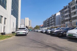 Una calle bordeada por coches aparcados y edificios de varios pisos.