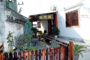 A traditional building with a wooden gate, a signboard, and potted plants. - Kelaiju Inn (Suzhou)
