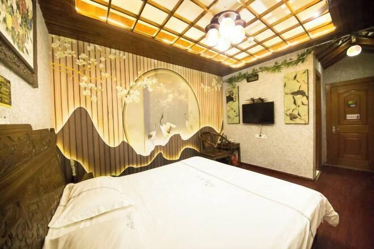 Une chambre à coucher avec un lit, un grand miroir, une télévision et une porte en bois.