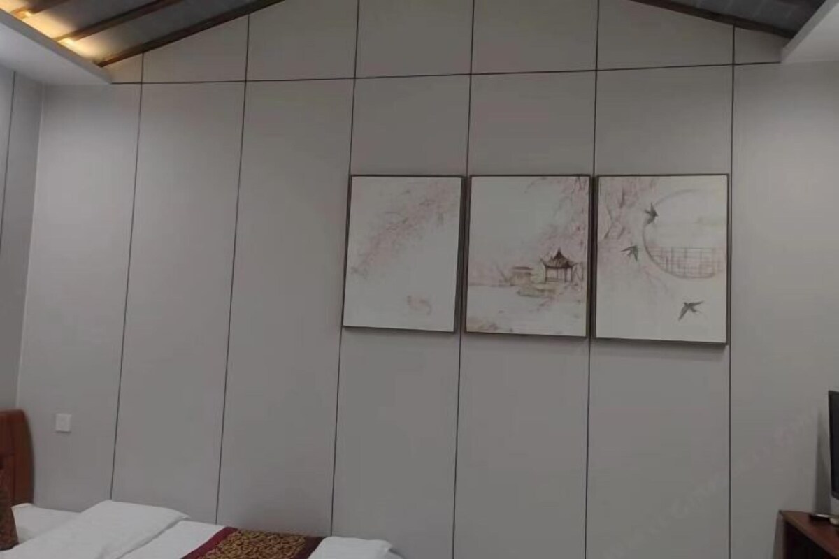 A hotel room with a bed, a TV, and a wall with three framed artworks.