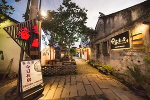A narrow alleyway with a traditional building on the right, a signboard on the left, and a tree in the center. - Kelaiju Inn (Suzhou)