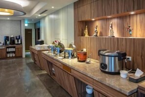 A modern kitchen with a long countertop, coffee machines, and a slow cooker. - Cloud Hotel (Taipei)