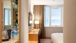 A hotel room with a bed, a desk, a chair, a mirror, a window, and a lamp. - Cloud Hotel (Taipei)