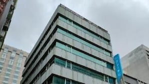 A multi-story building with a modern architectural design, featuring a series of windows and a prominent blue sign on the facade. - Cloud Hotel (Taipei)