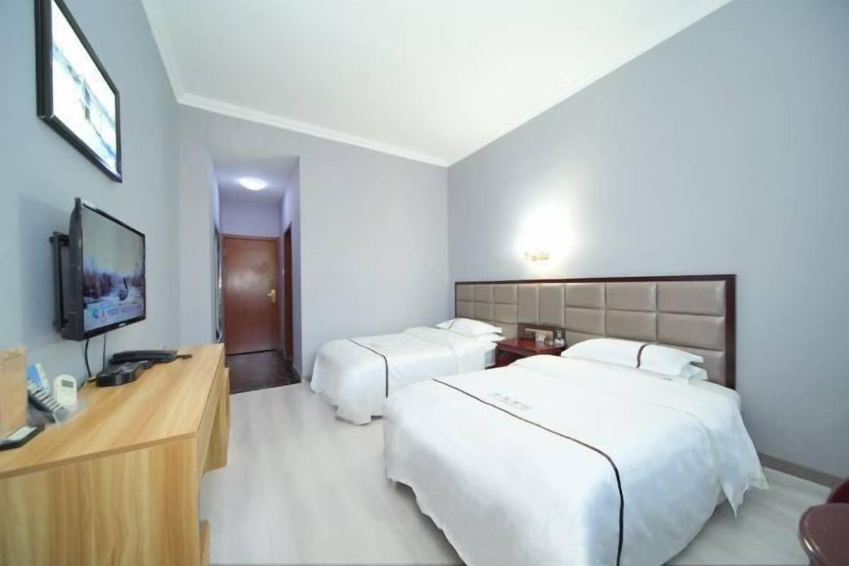 Una camera d'albergo con due letti, una scrivania con televisore e una zona reception.