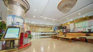 A lobby with a reception desk, seating area, and informational posters. - Jinghe Heli Hotel (Jinghe)
