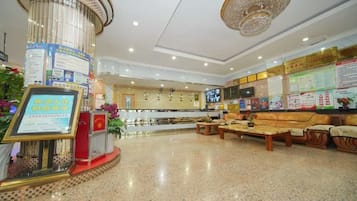 A hotel lobby with a reception desk, seating area, and informational displays.