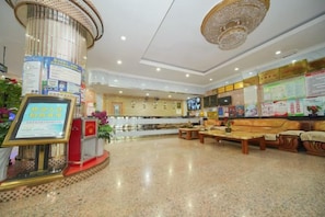 A hotel lobby with a reception desk, seating area, and informational displays. - Jinghe Heli Hotel (Jinghe)