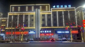 A hotel with multiple floors, illuminated signage, and a visible entrance. - Jinghe Heli Hotel (Jinghe)